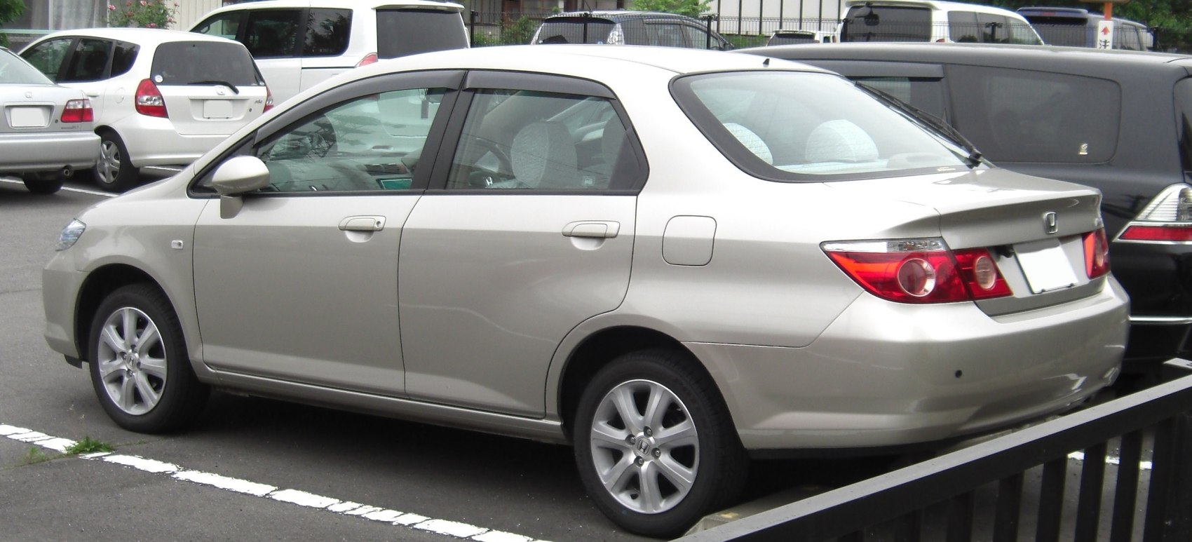 Rear side profile of a silver compact sedan with alloy wheels and tapered rear window.