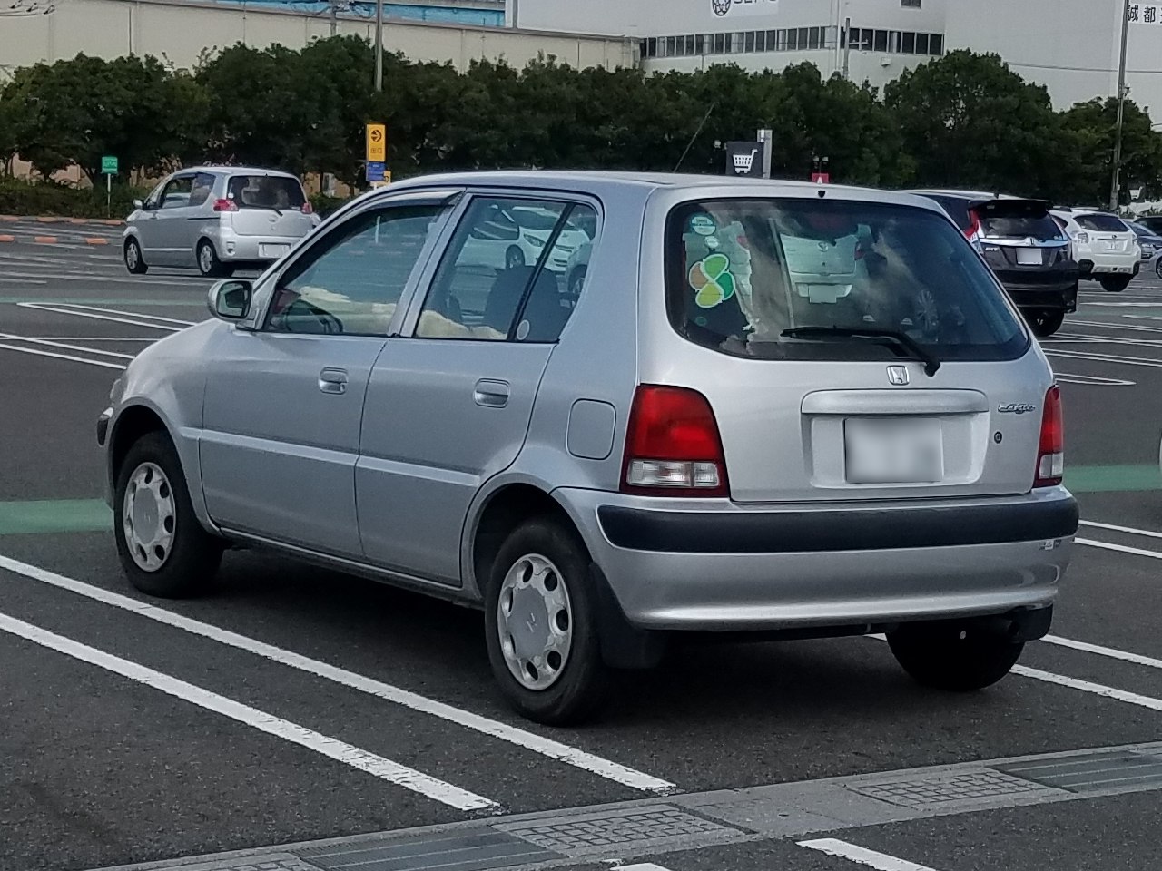 Compact silver hatchback rear side with classic tail lights and simple bumper.