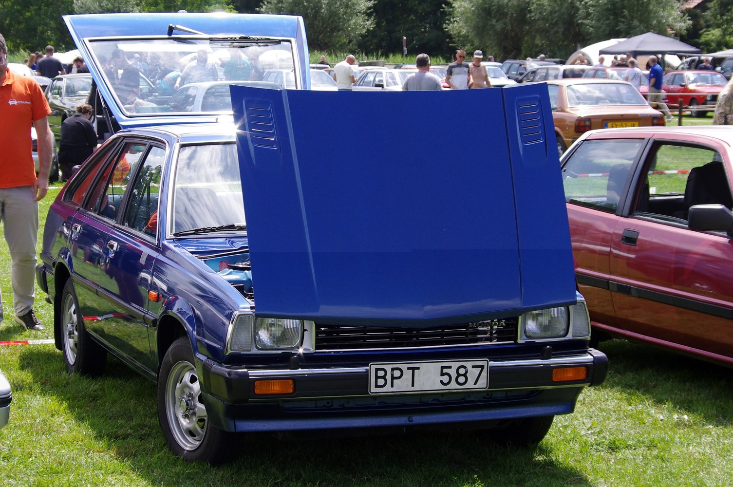 Station wagon with hood and rear hatch open in outdoor setting