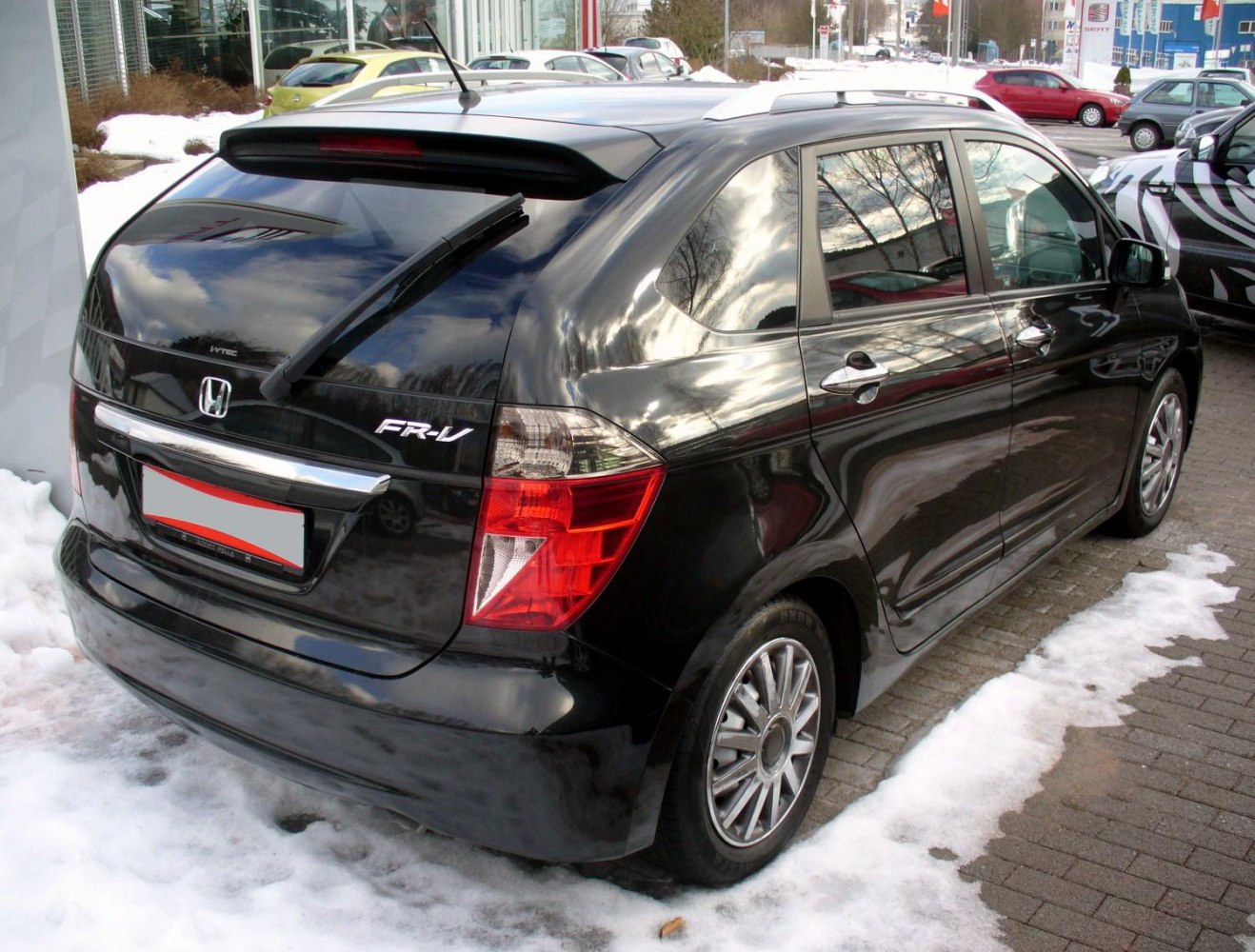 Rear view showing roof spoiler and tail lights on black hatchback