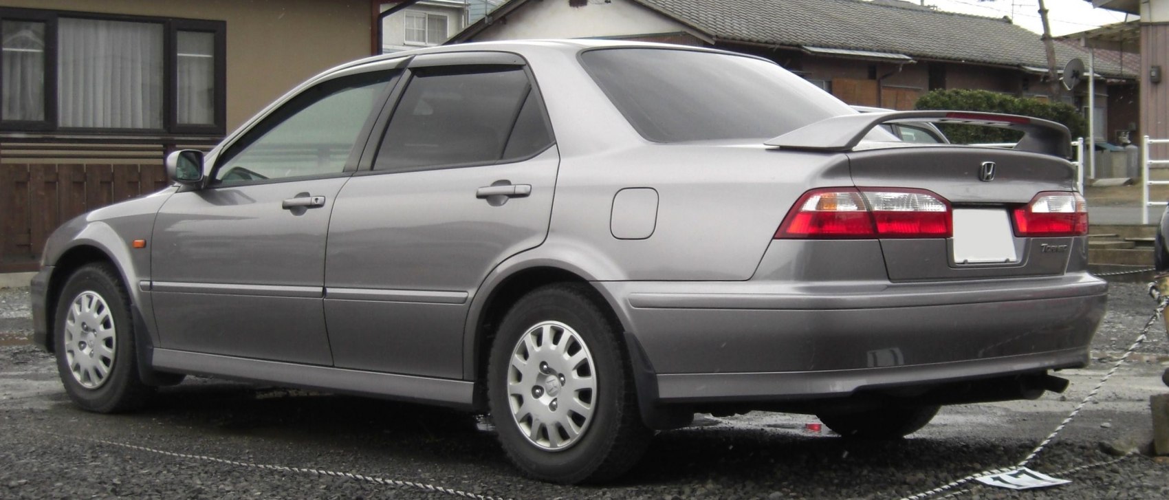 Rear side of mid-size sedan with spoiler and alloy wheels