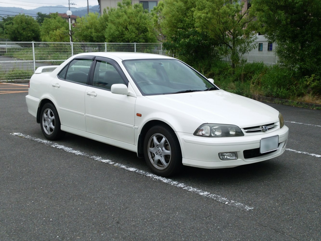 White sedan with rear spoiler and alloy wheels