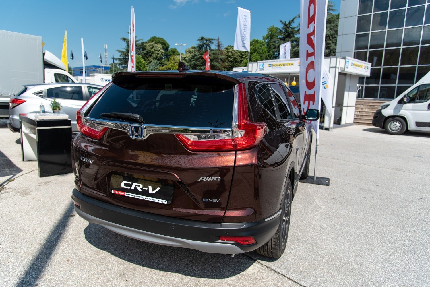 Rear view with AWD and hybrid badges, unique L-shaped taillights, dark brown exterior