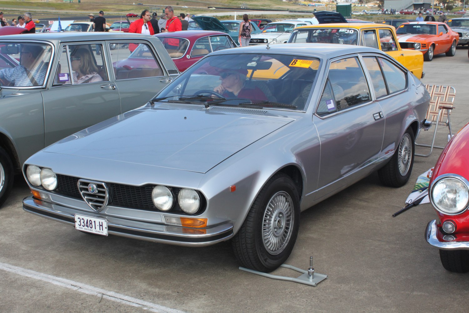 Silver vintage coupe with quad round headlights and aerodynamic body.