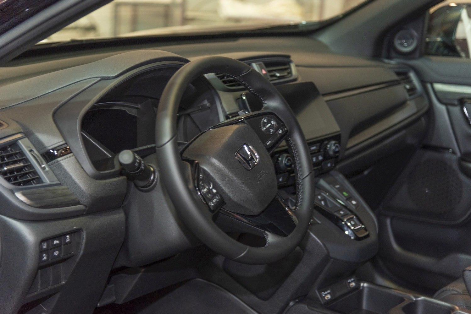 Modern car steering wheel and dashboard with control buttons.