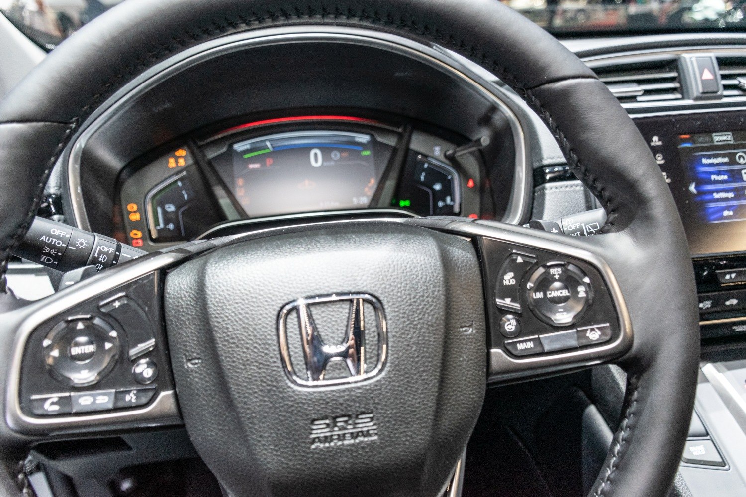 Steering wheel with control buttons and digital dashboard display.
