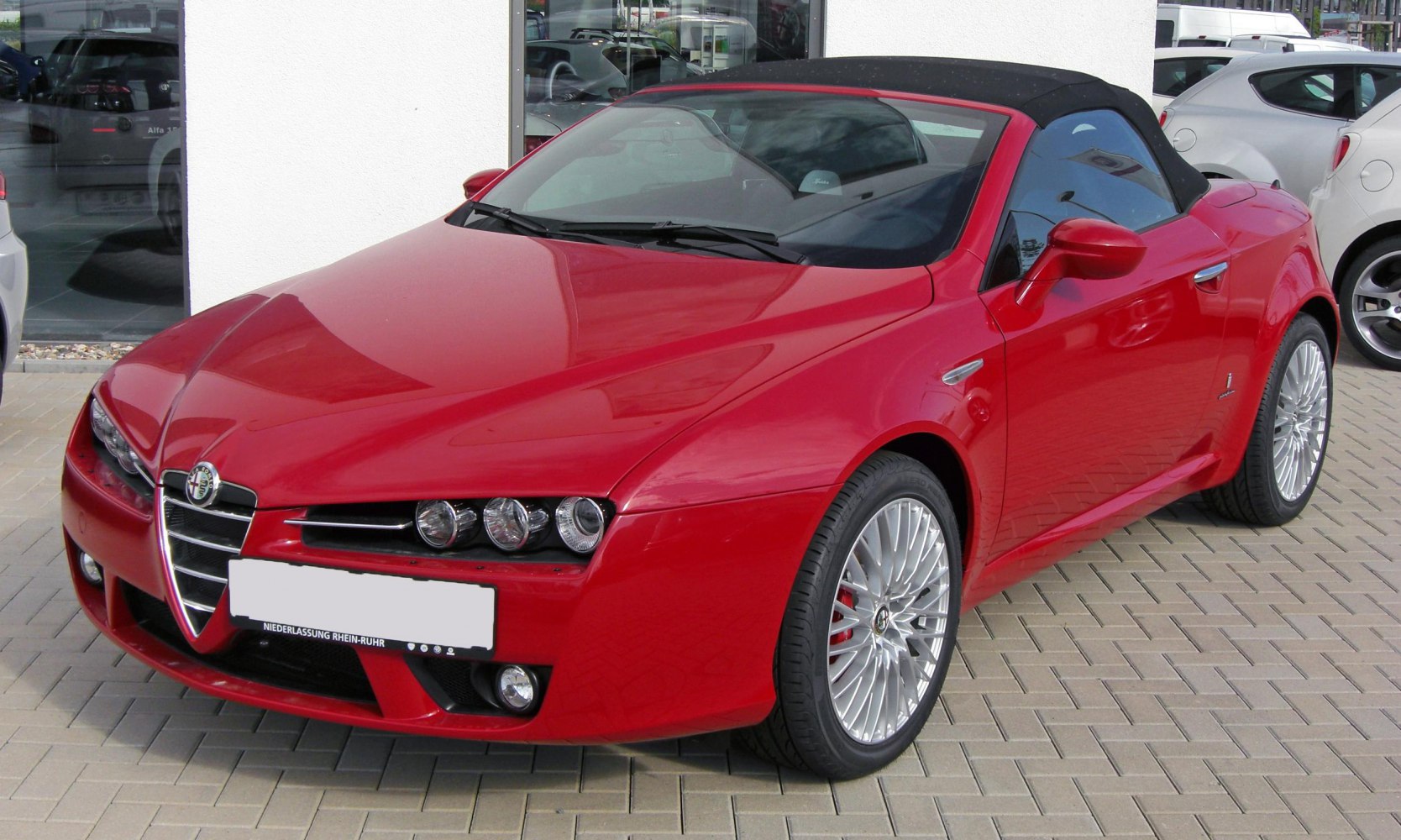 Red convertible with tri-headlight front and alloy wheels