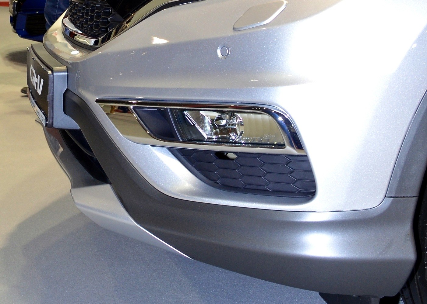 Close-up of front fog light and bumper with hex-pattern grille