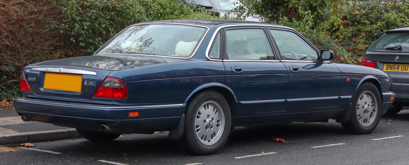 Rear side profile of a blue luxury sedan with distinctive taillights and alloy wheels
