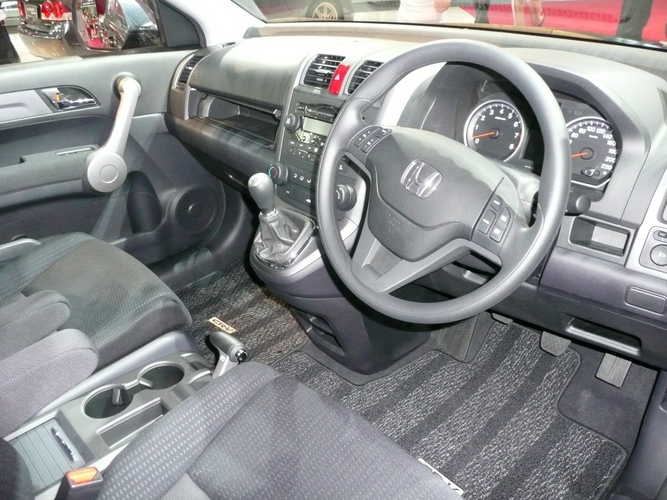 Dashboard and steering wheel with manual gearshift and instrument panel.