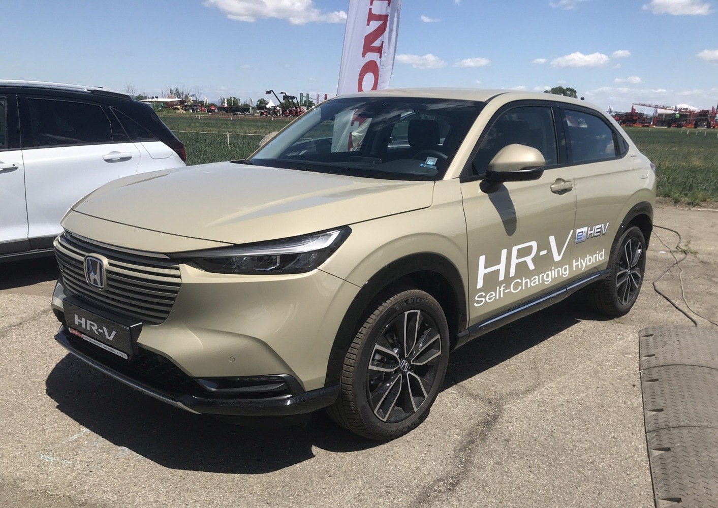 Front-side view of beige self-charging hybrid crossover with LED headlights