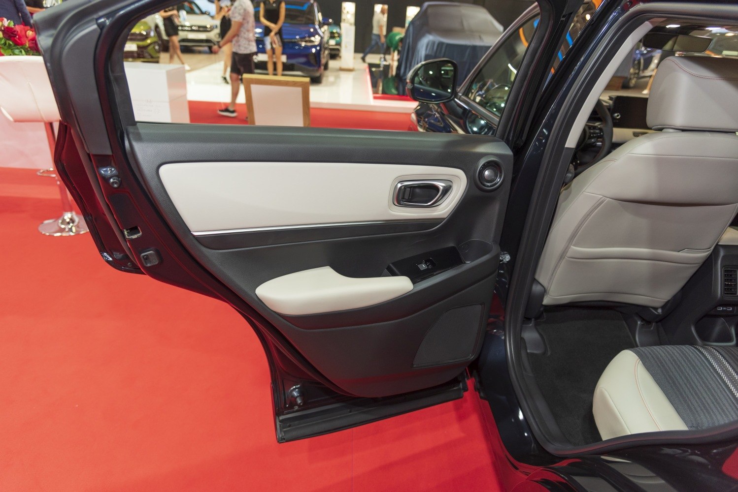 Rear door interior with handle, armrest, speaker, and beige-black panel
