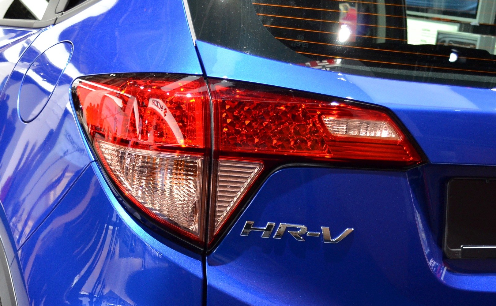 Close-up of rear tail light and badge on blue vehicle rear side