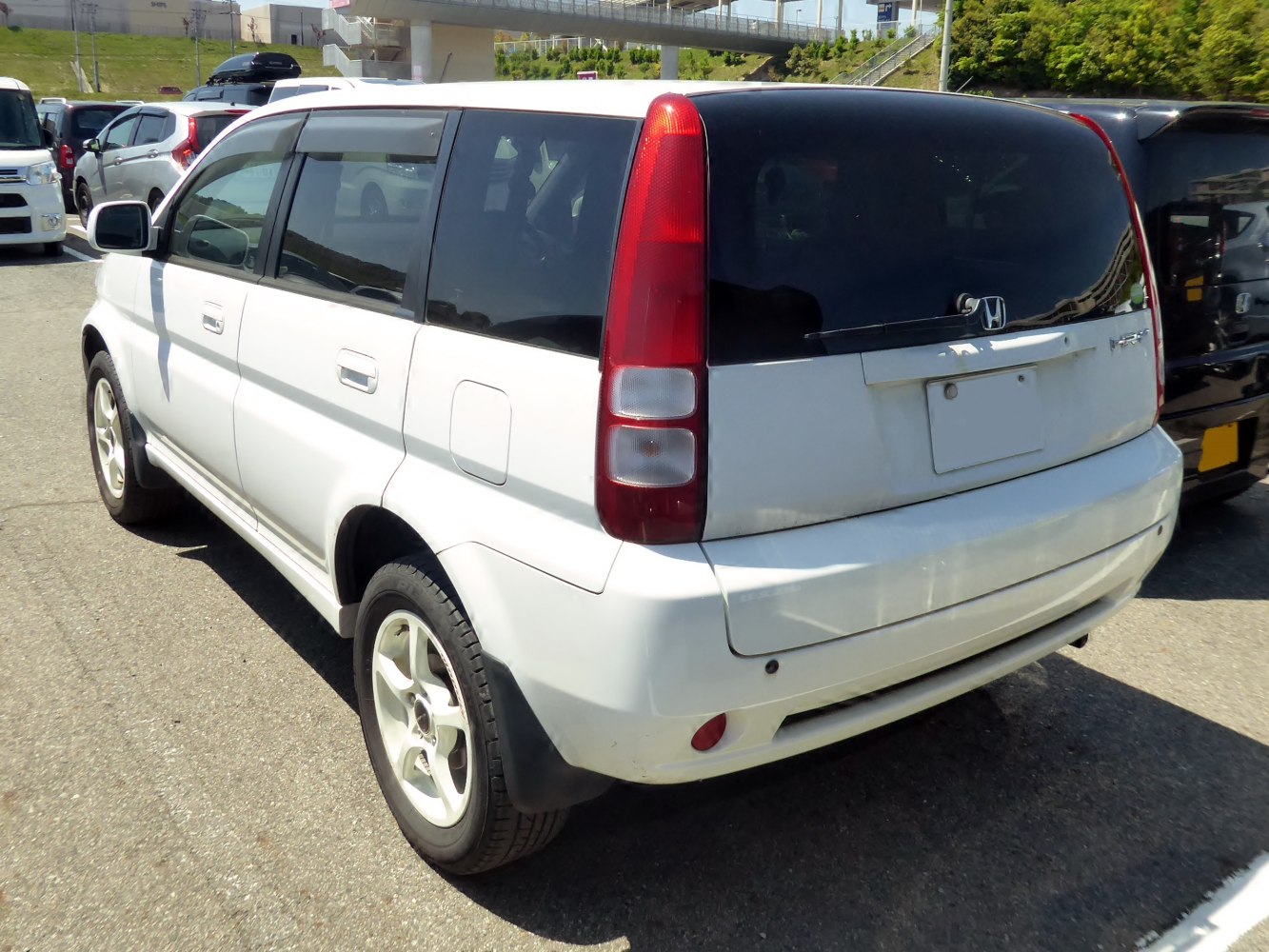 Rear side view of white compact SUV with vertical taillights