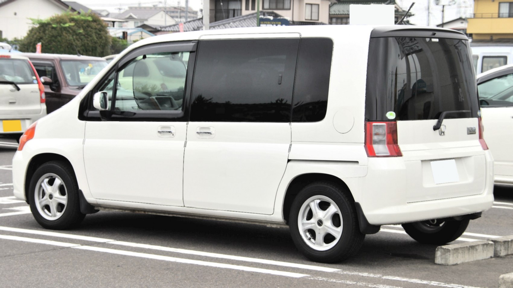 Side and rear view of a white compact MPV with sliding doors