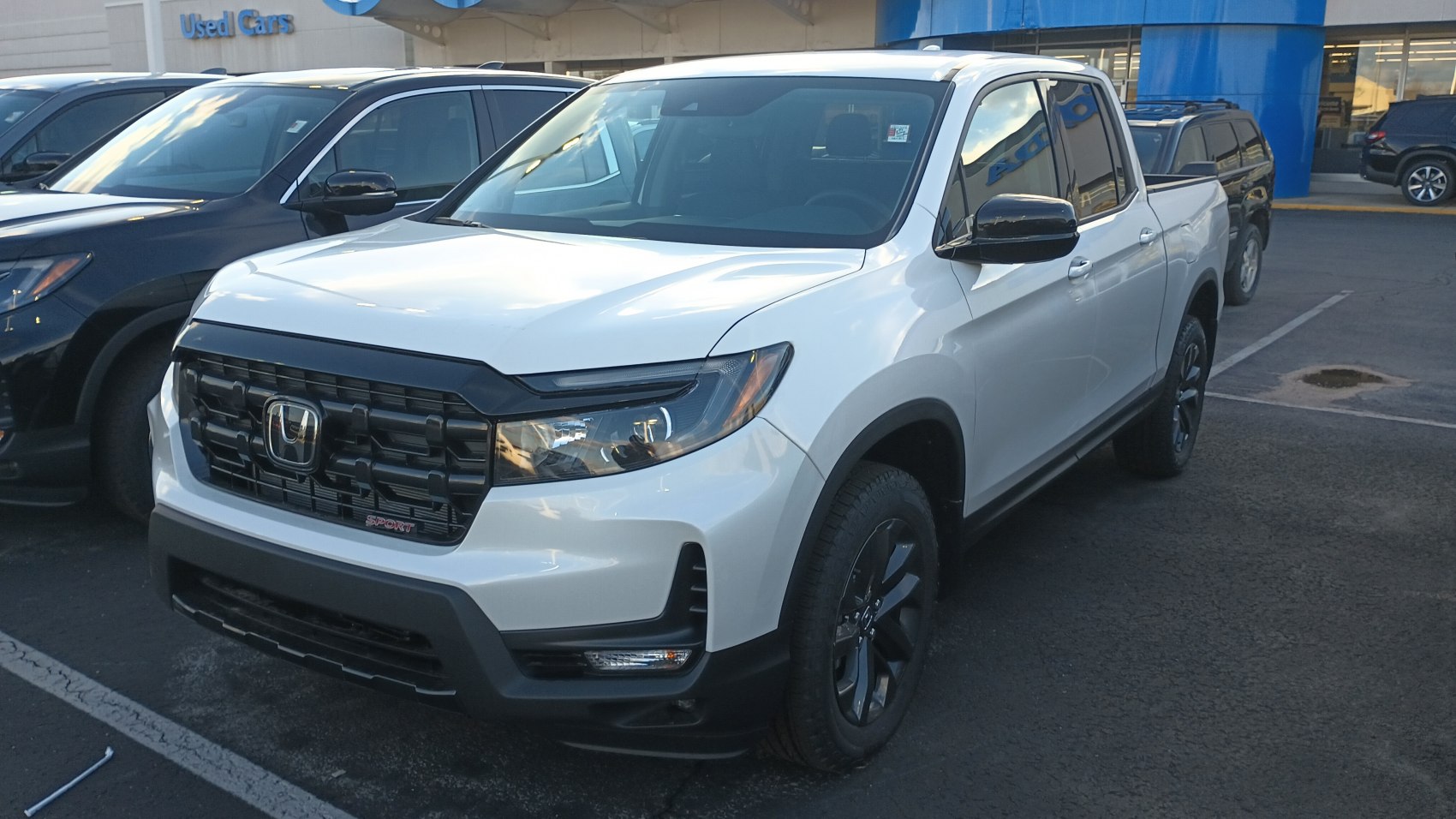 Sporty black grille and headlights on a white midsize pickup truck front.