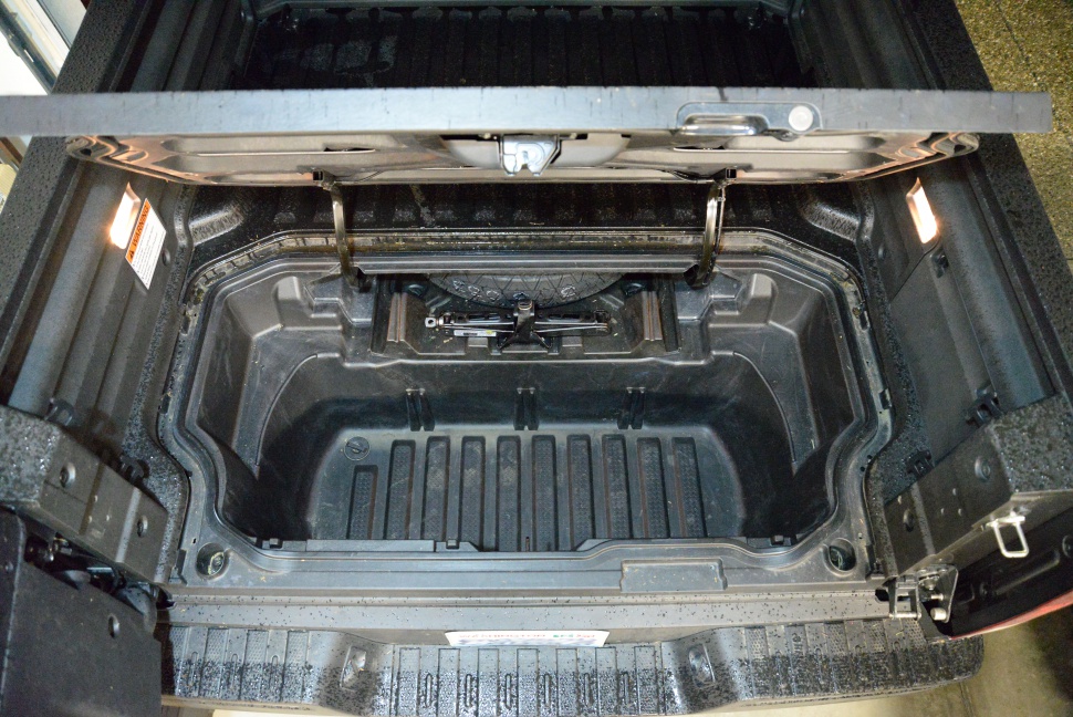In-bed trunk storage compartment with lighting and jack tool