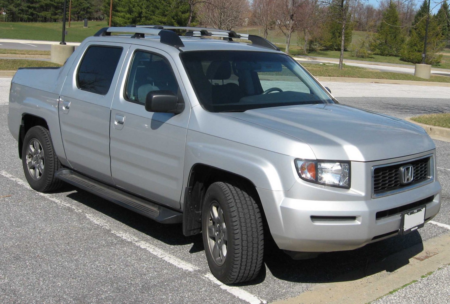 Silver pickup with roof rack, front side view showing grille and large tires