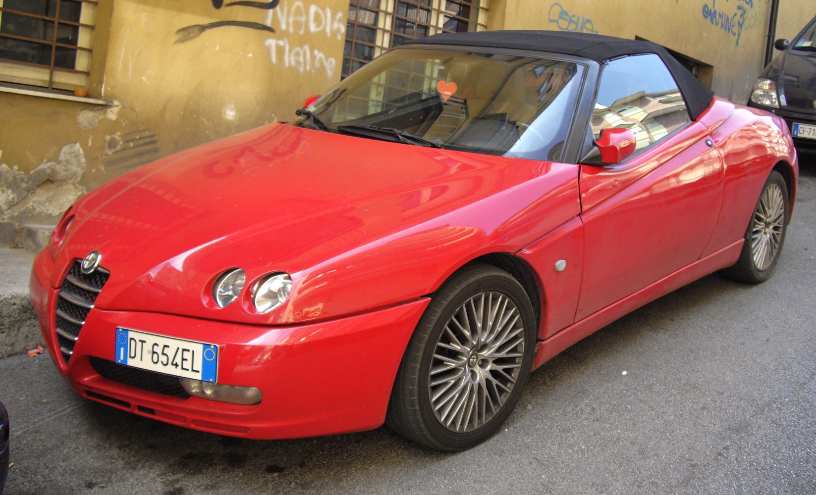 Red convertible with dual round headlights and soft top roof