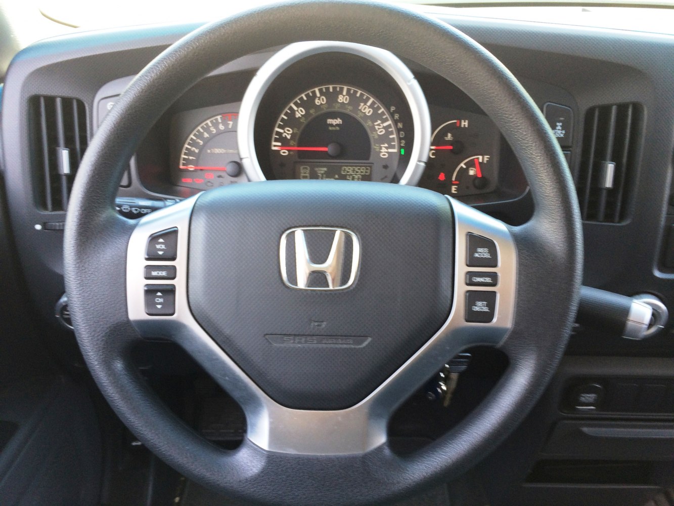Steering wheel with controls and dashboard instrument cluster in vehicle interior