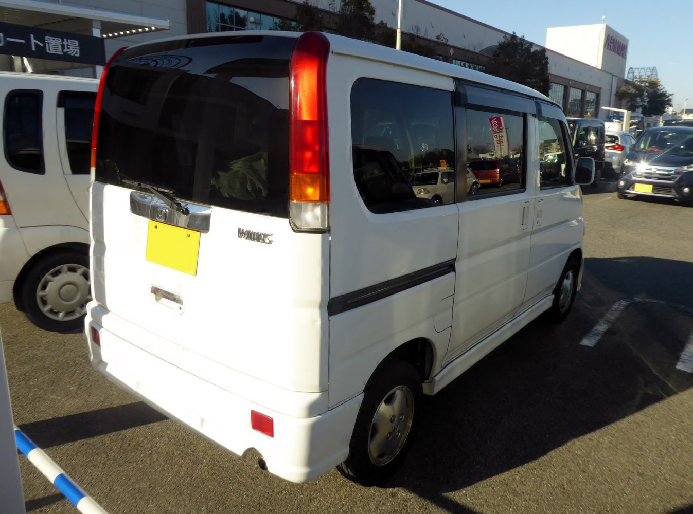 Rear view with prominent vertical tail lights and sliding side door on compact mini van