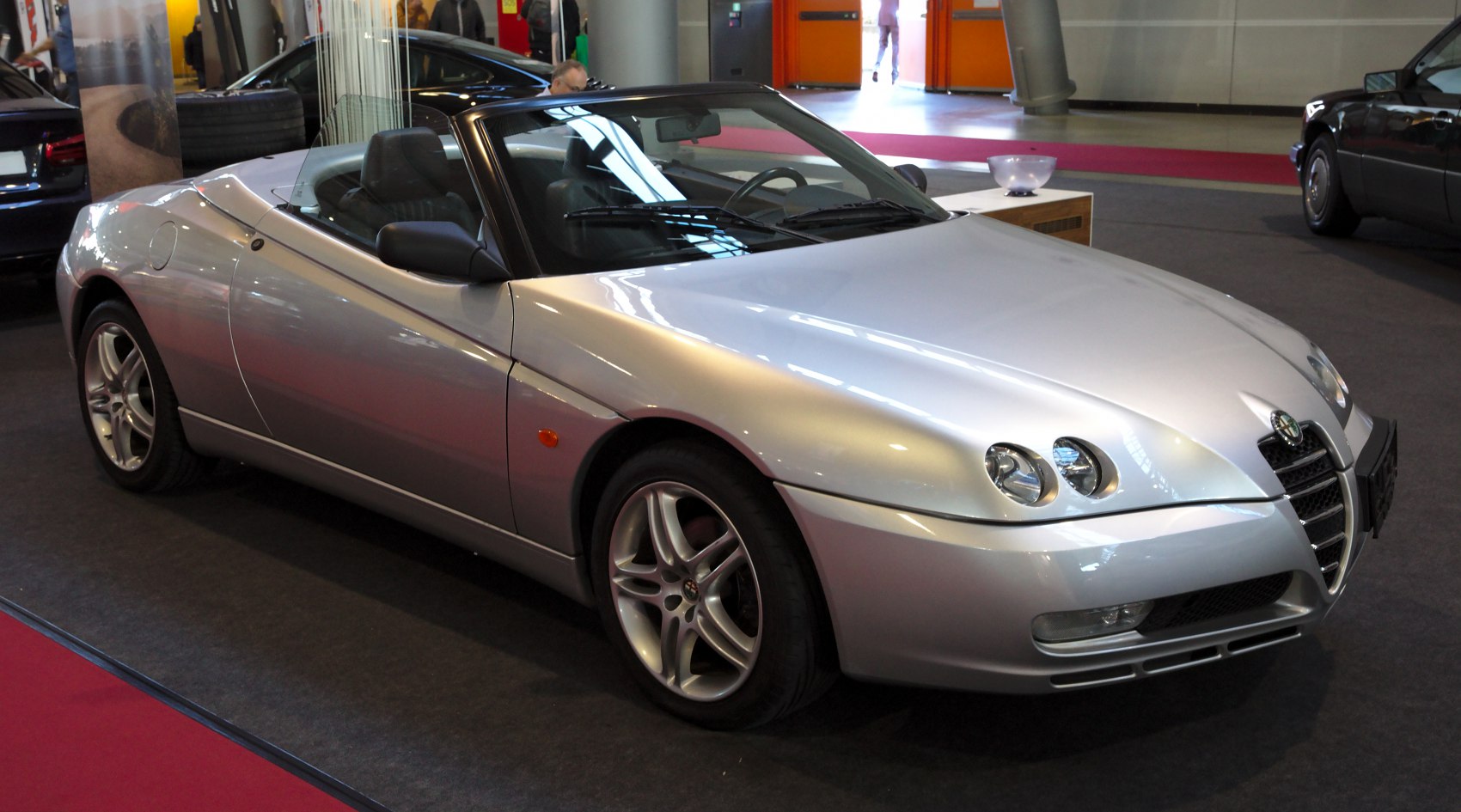 Silver convertible with dual round front headlights and aerodynamic design.