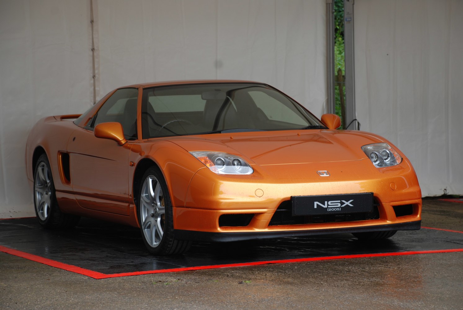 Front 3/4 view of orange sports coupe with sleek headlights and aerodynamic styling