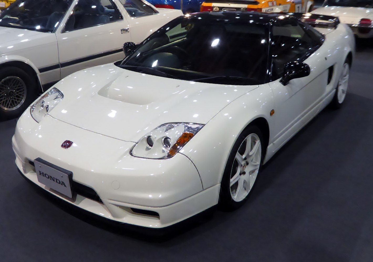Front three-quarter view of white sports coupe with aerodynamic hood and sleek headlights