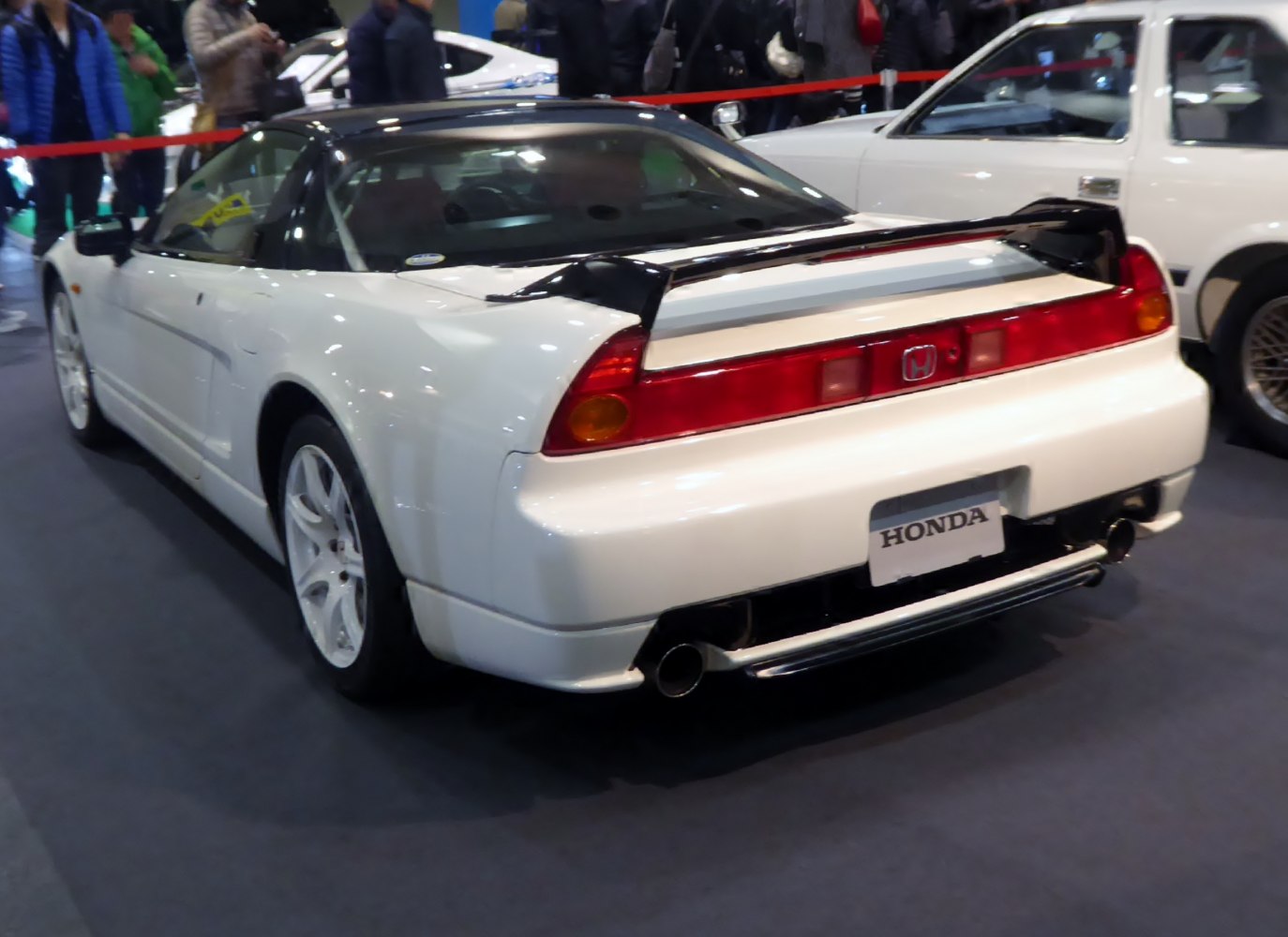 Rear view with black spoiler and dual exhausts on white sports car