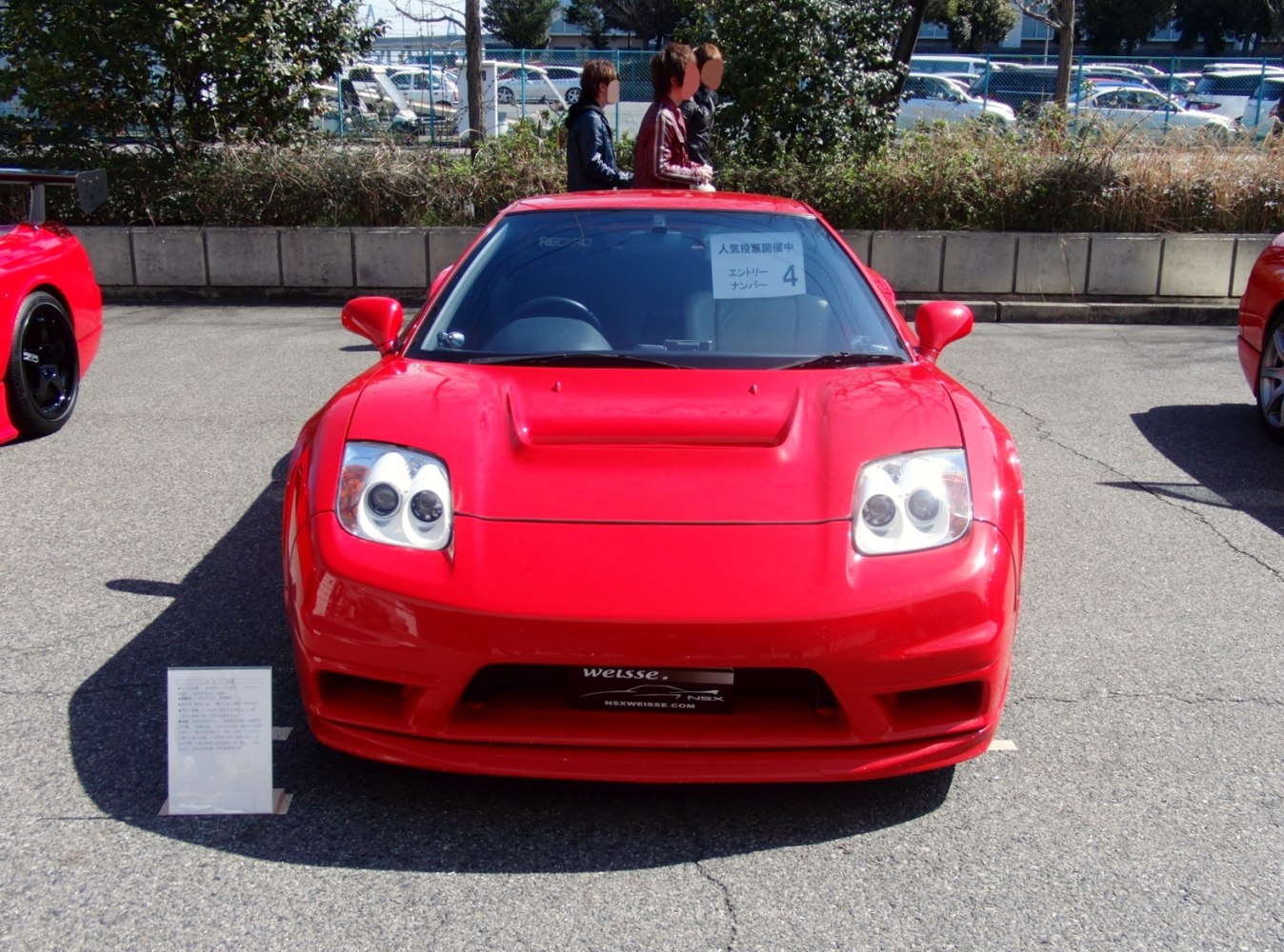 Front view of red sports coupe with dual round headlights and air vent hood.