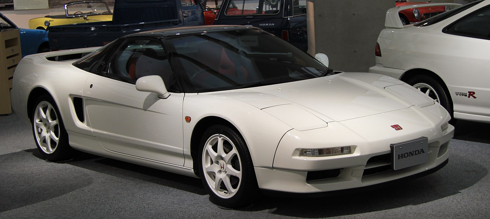 Sleek white mid-engine coupe with aerodynamic body and pop-up headlights.