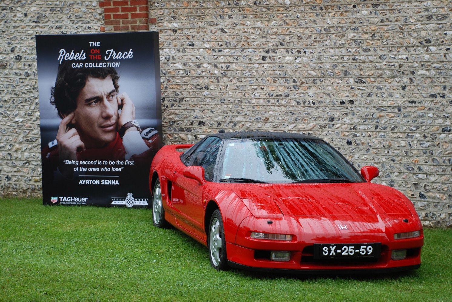 Red mid-engine sports coupe with sleek 1990 design and raindrops.