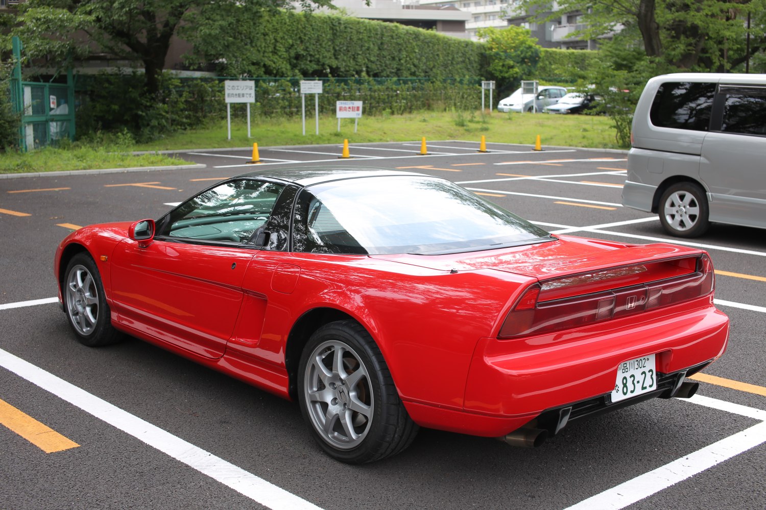 Rear-side view of a red sporty coupe with distinctive tail lights and a sleek roofline.