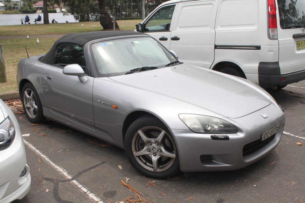 Silver convertible sports car with soft top roof and alloy wheels parked.