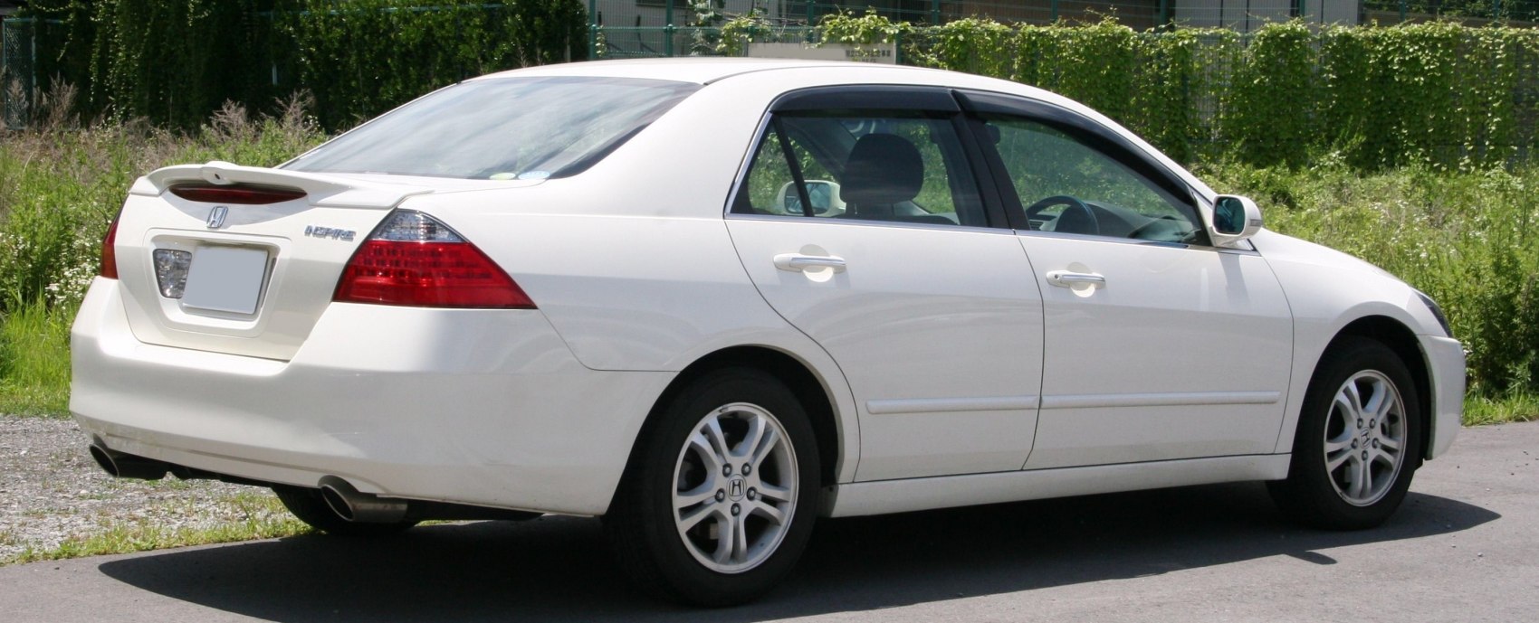 White sedan with rear spoiler and dual exhaust pipes