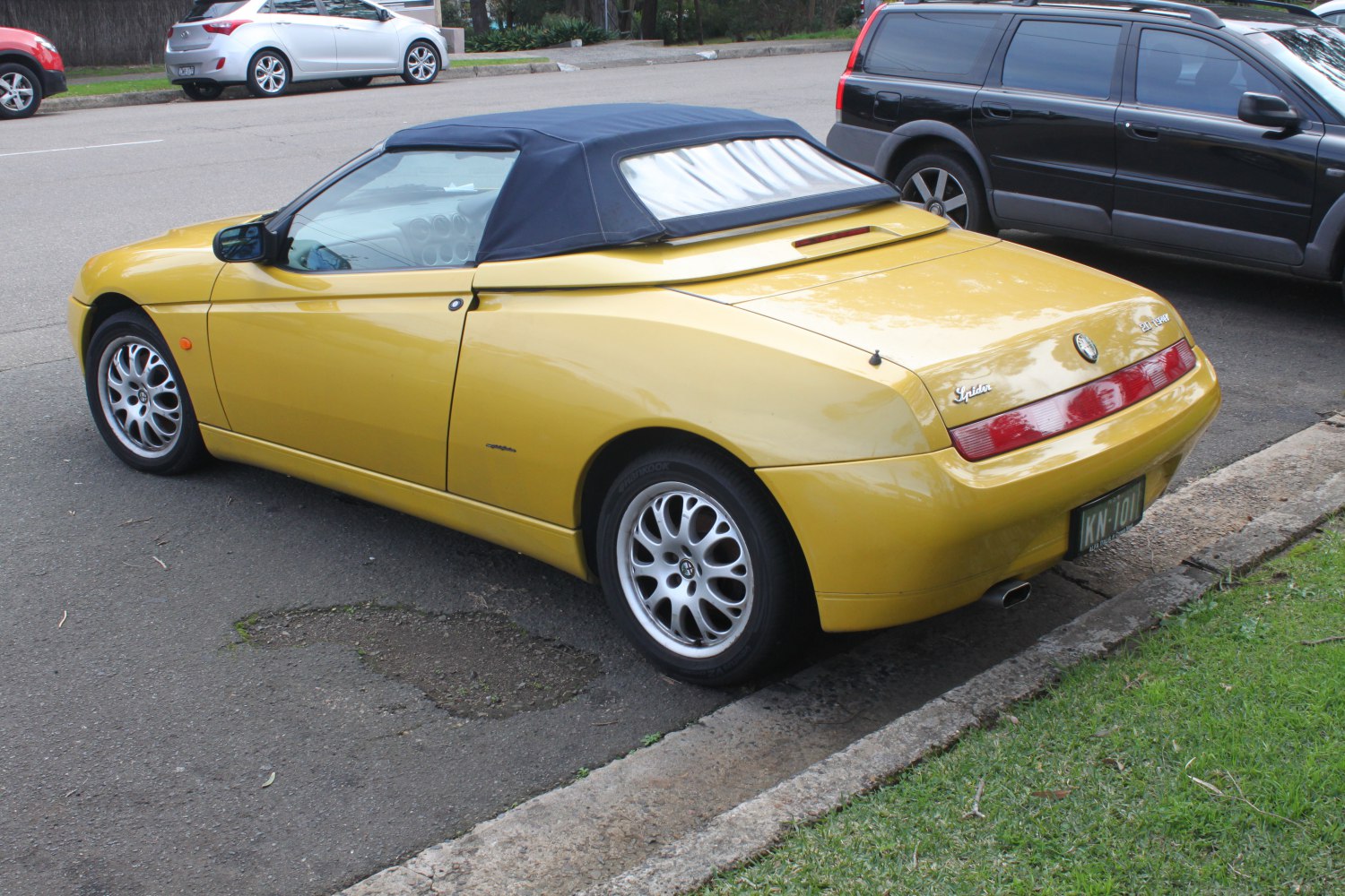 Yellow convertible with soft top and alloy wheels rear view