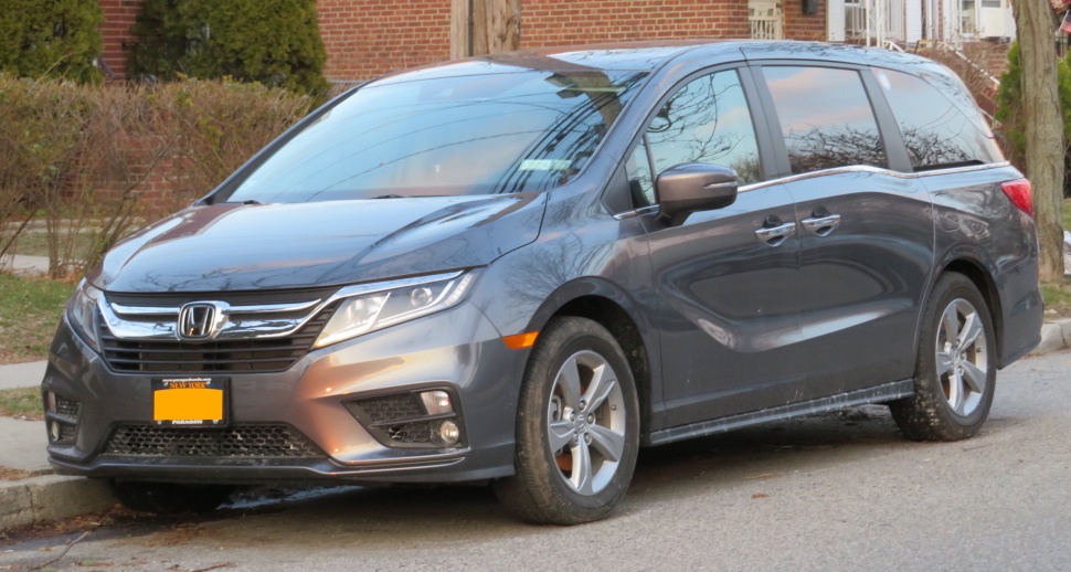 Minivan front side with grille, headlights, and alloy wheels