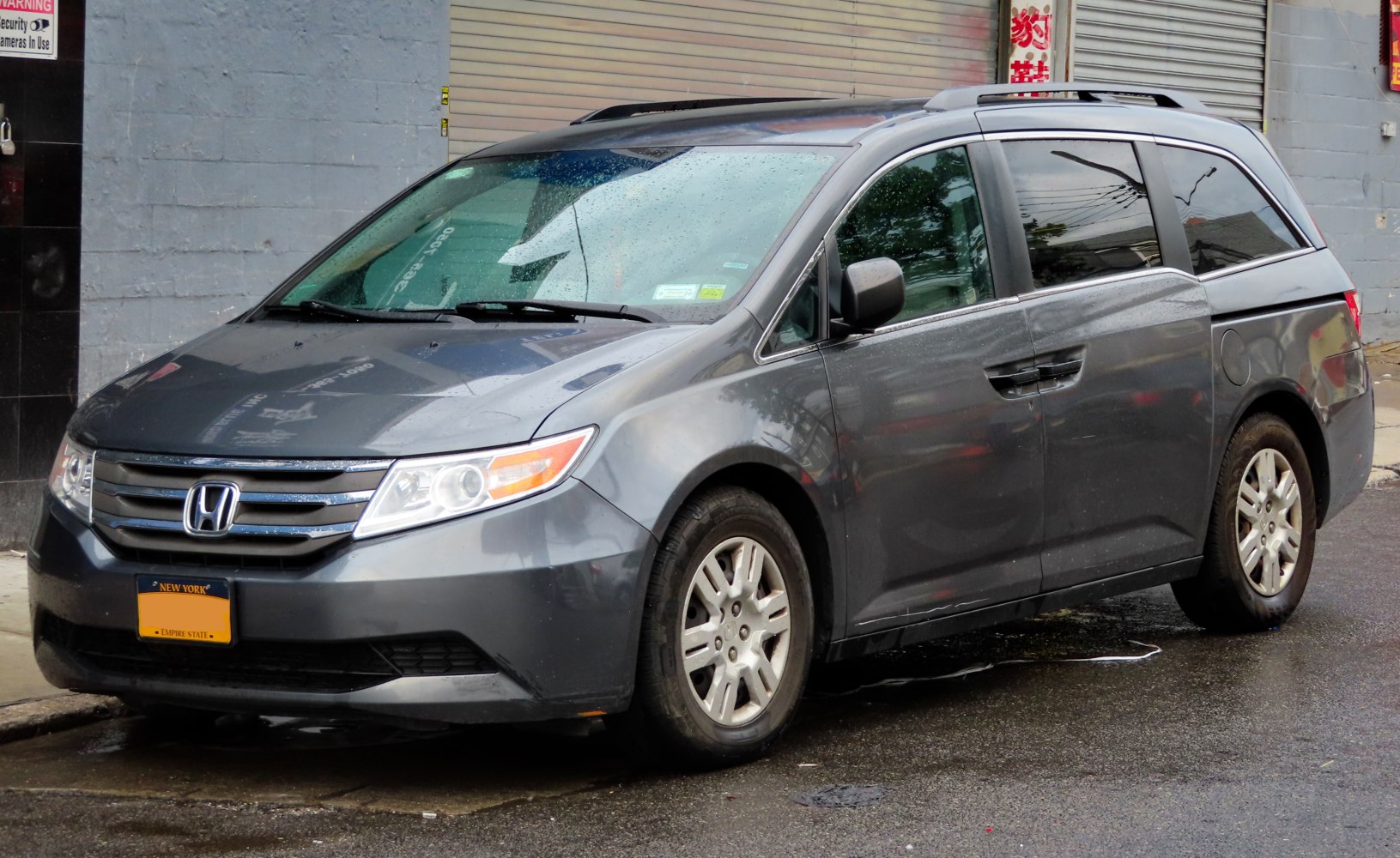Front and side view of a minivan parked on wet street