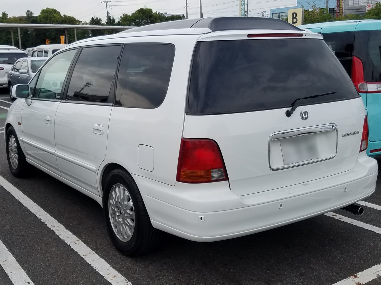 Rear and side view of white minivan with tinted windows and tail lights