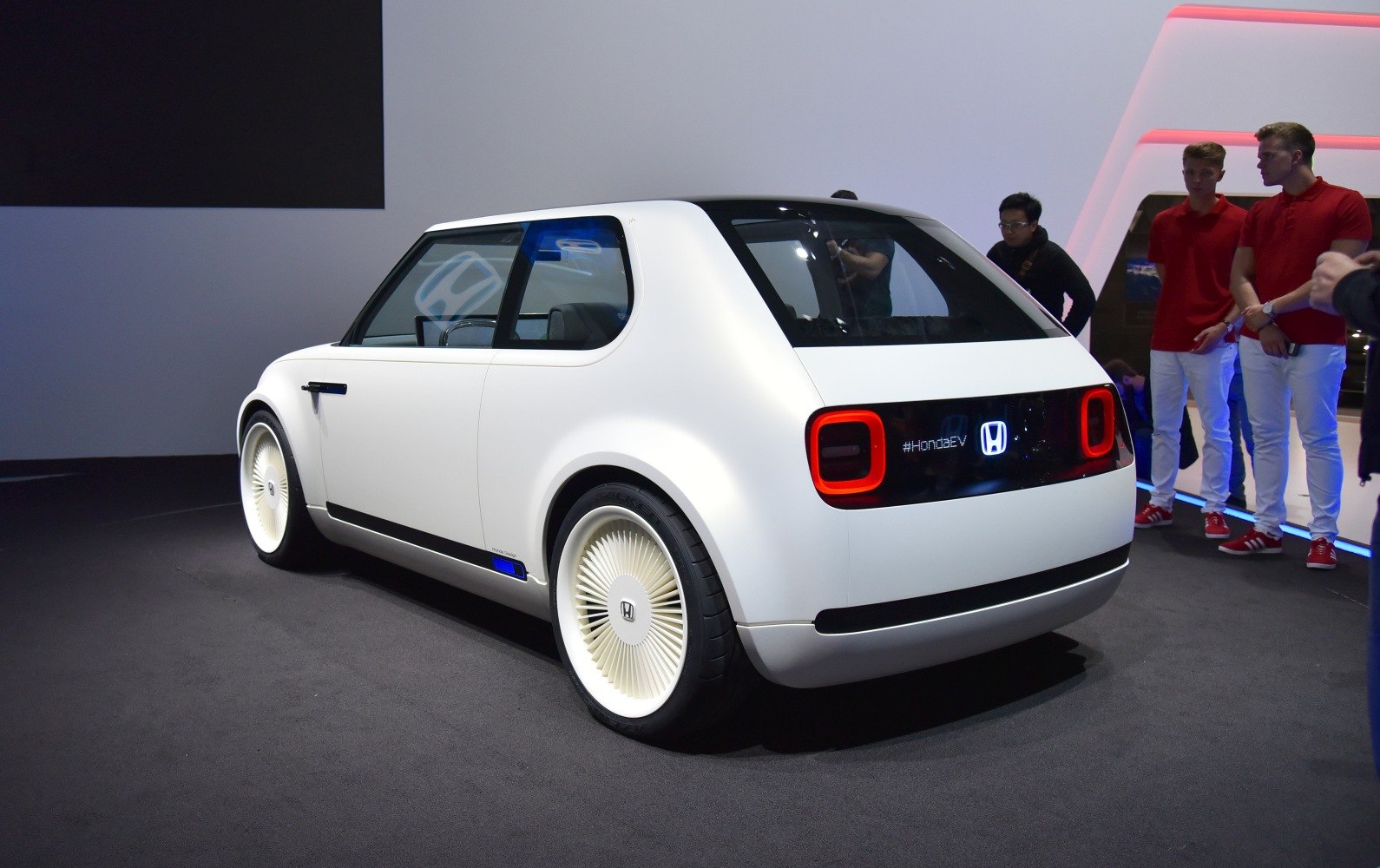 Compact electric vehicle with retro-futuristic design and distinctive rear LED lights.