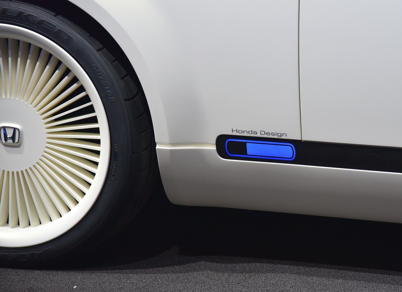 White spoke wheel and blue accent lighting on vehicle side panel.