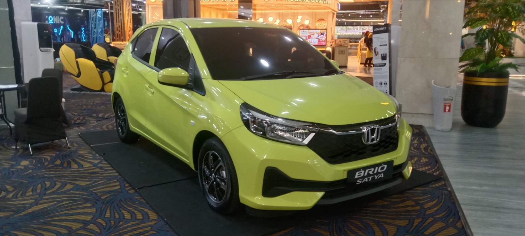 Lime green hatchback front profile with modern headlamps and sporty grille.