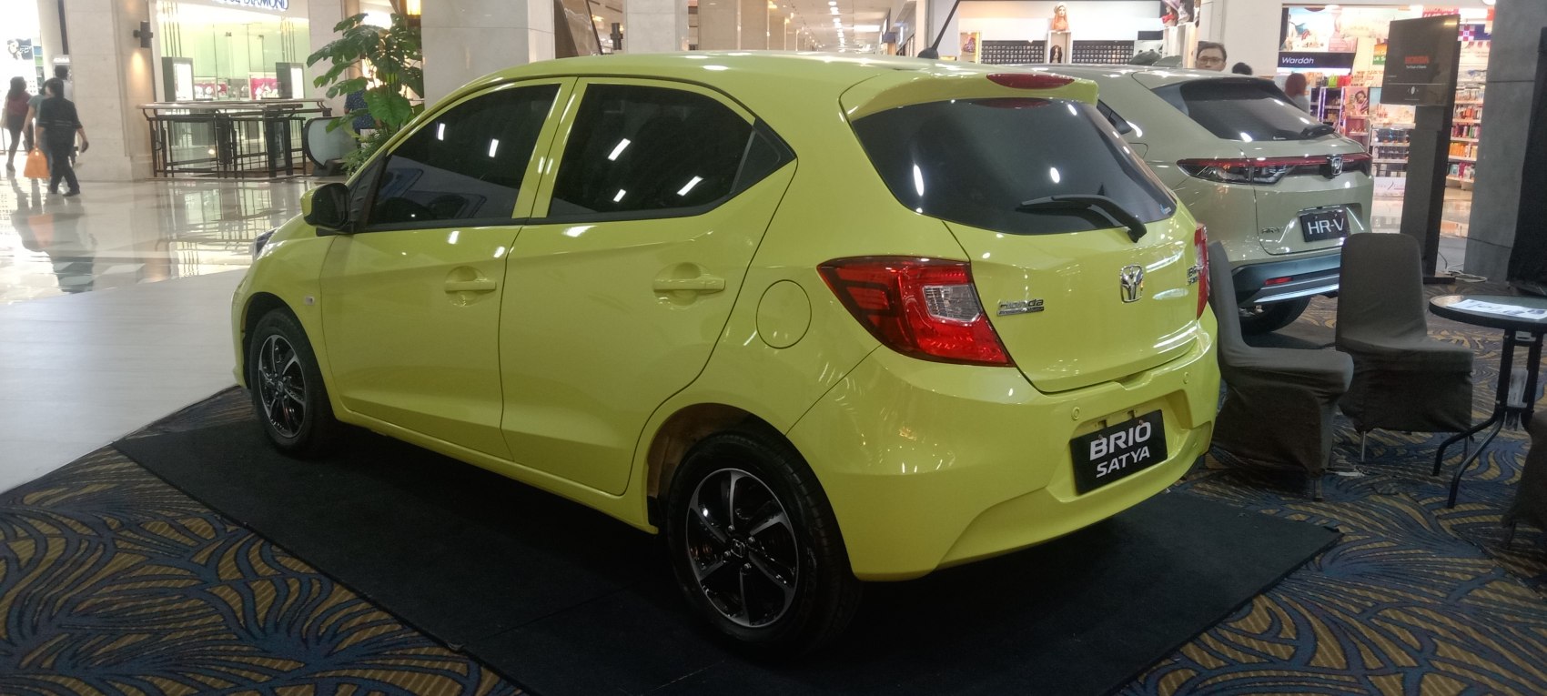 Rear three-quarter view of a yellow compact hatchback with tinted windows and black alloy wheels.