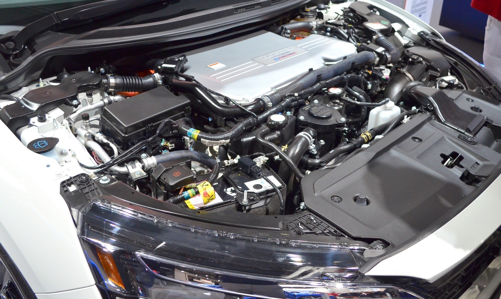 Engine bay with hybrid powertrain and front headlight assembly