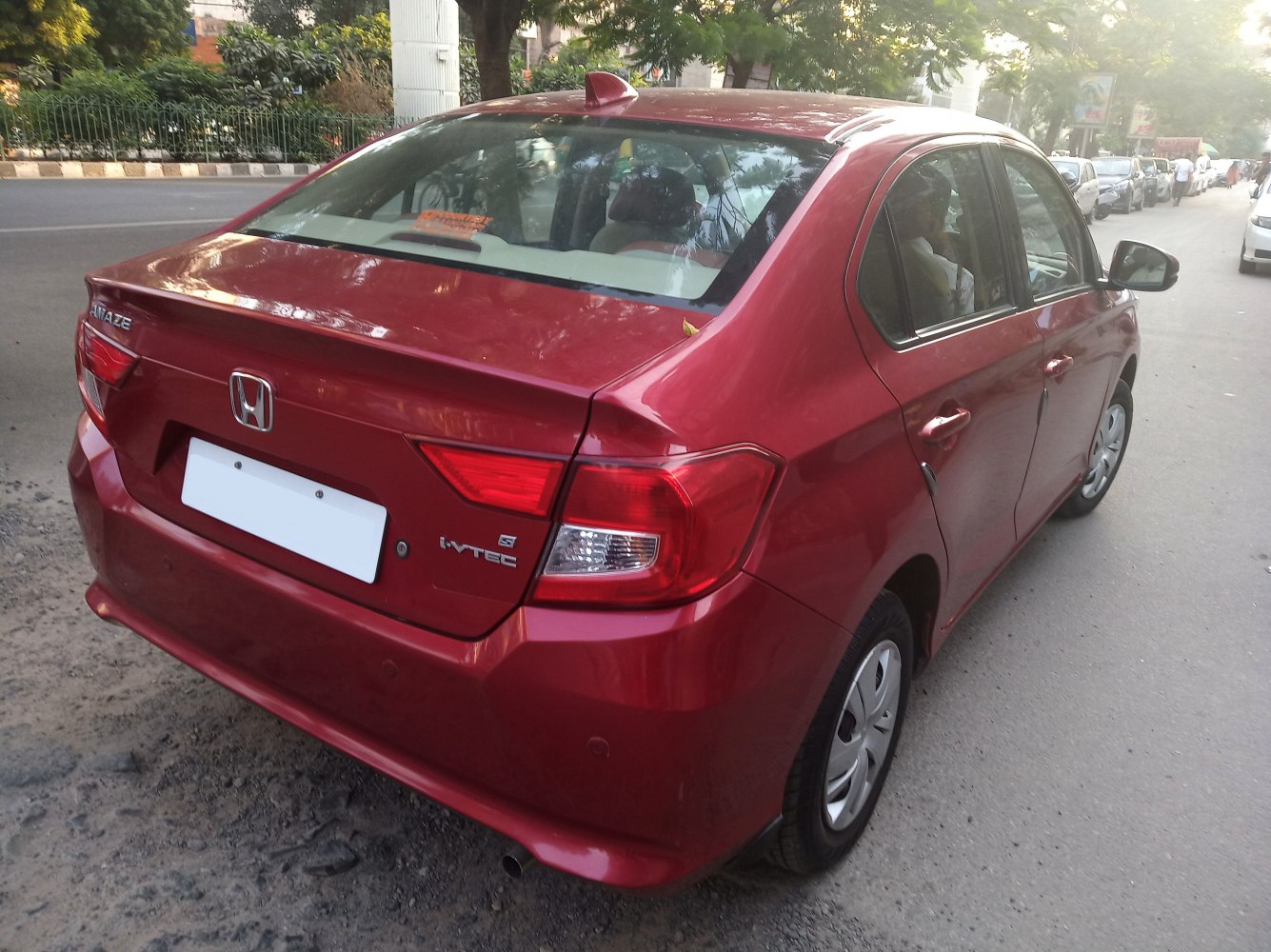 Rear side view of a red compact sedan with tail lights and trunk details