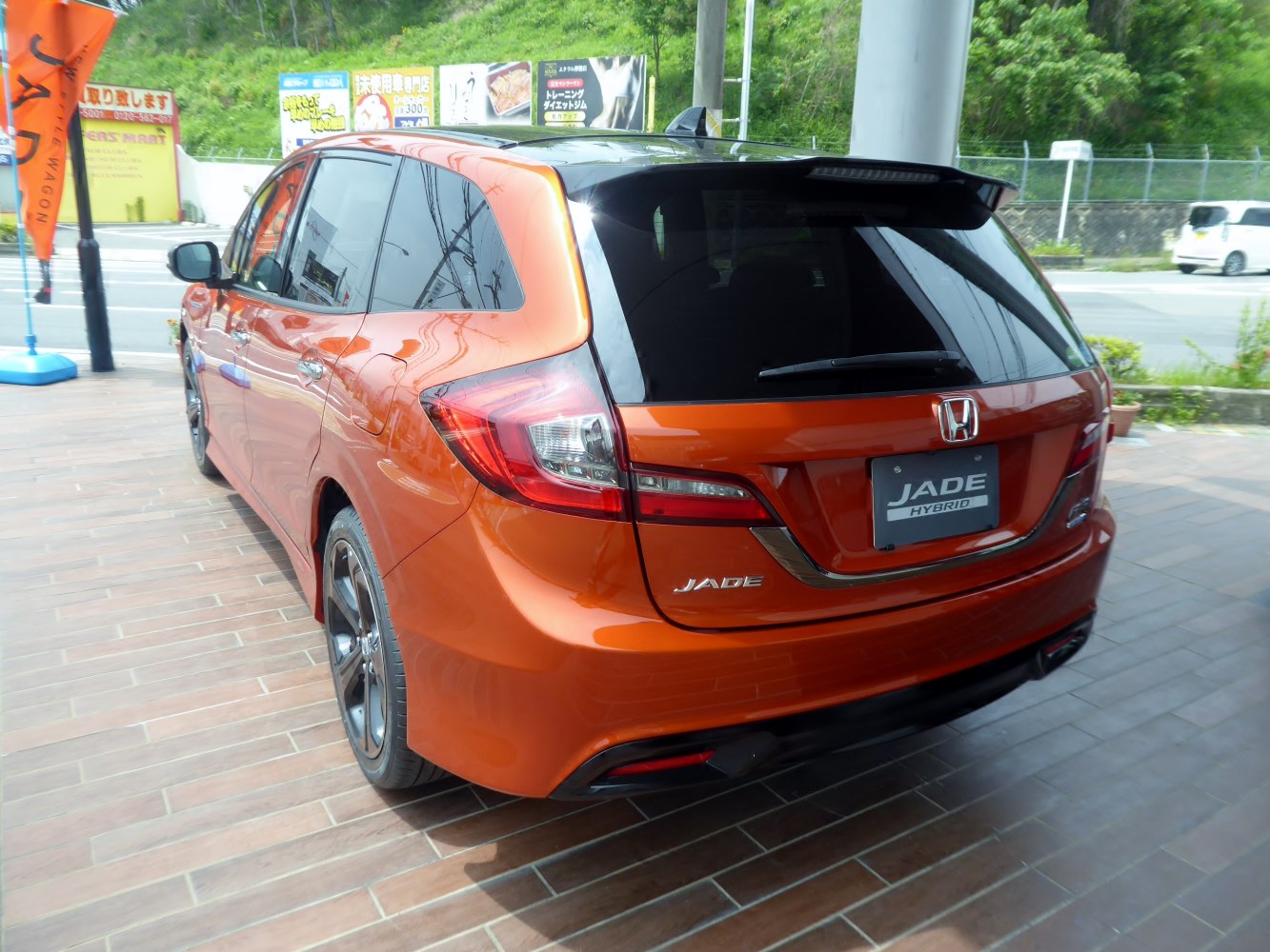 Rear view of orange hatchback with hybrid badge and sporty tail lights