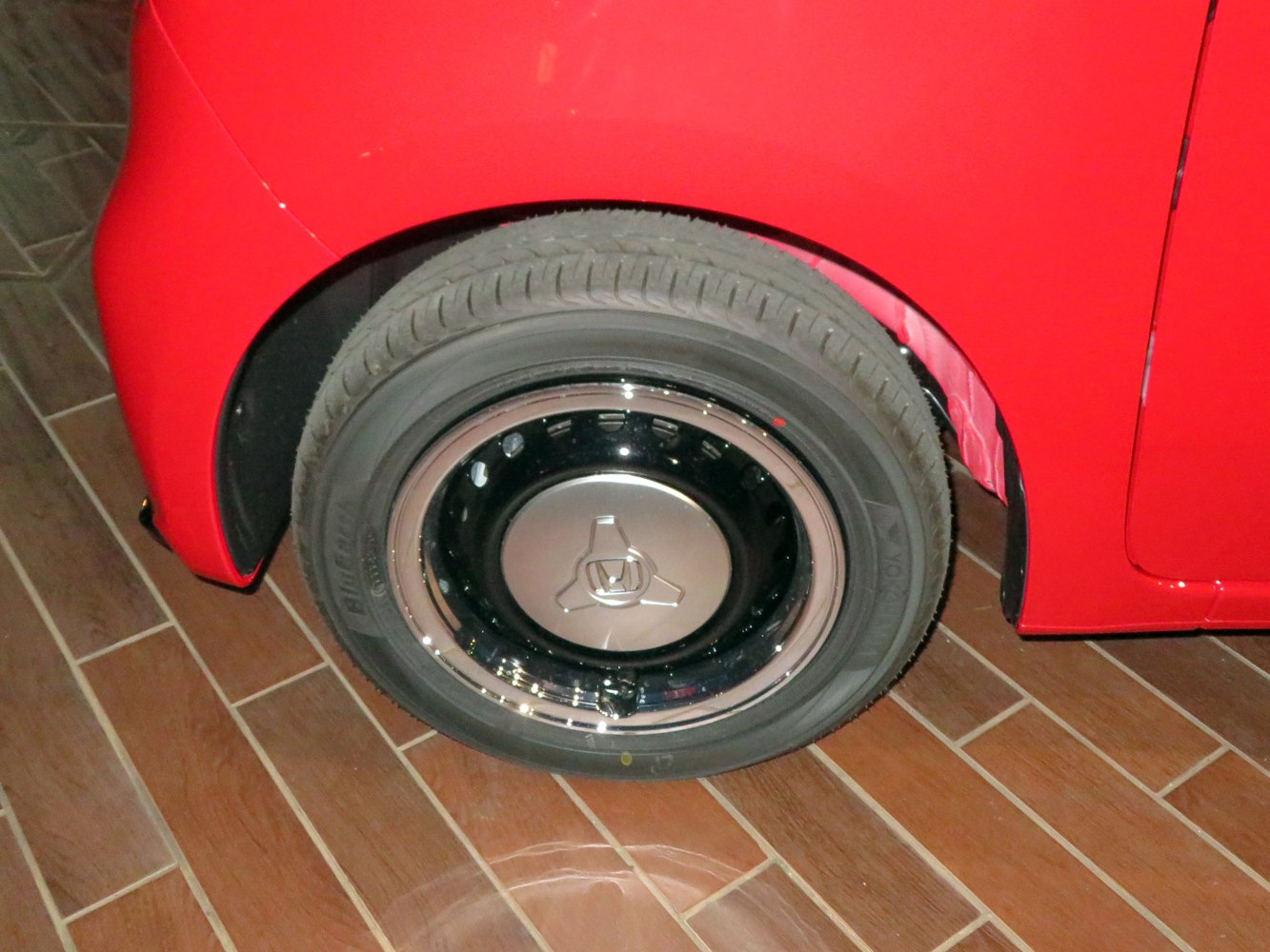 Close-up of steel wheel with hubcap and tire on car rear quarter panel