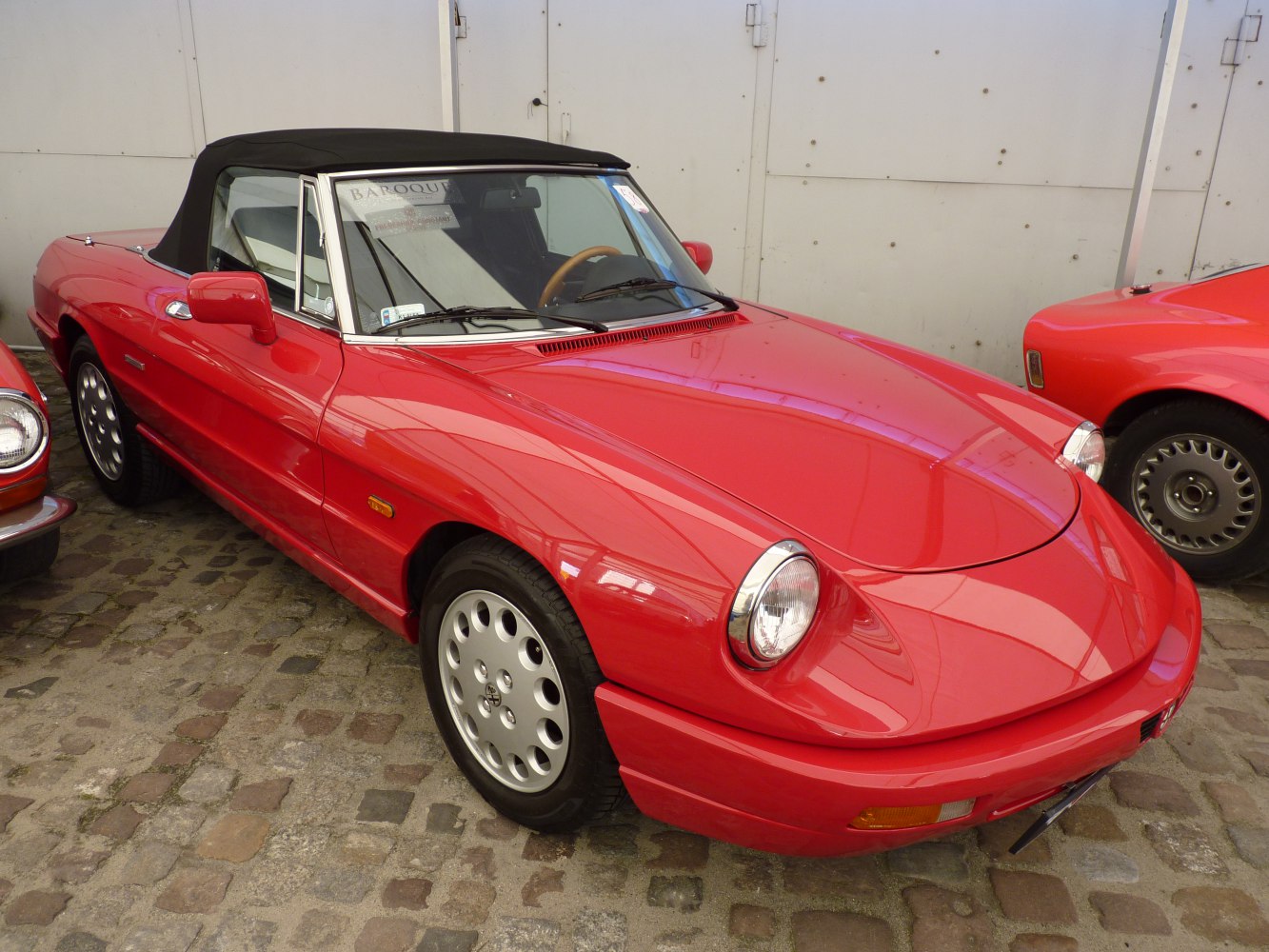 Red convertible with black soft top and round headlights