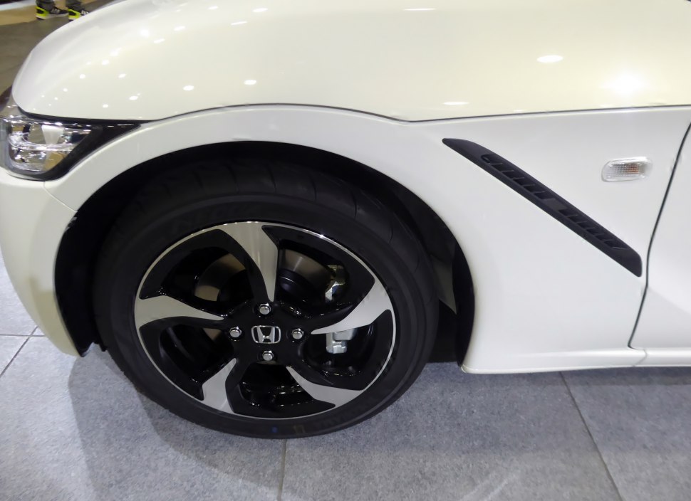 Close-up of front wheel and side fender vent with alloy rim design