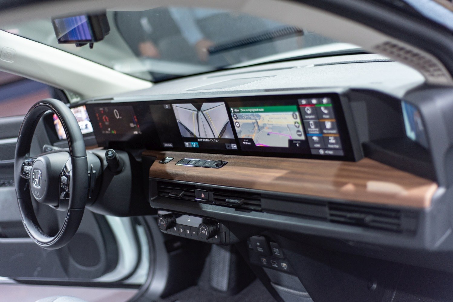 Modern dashboard with three digital displays and wood trim.